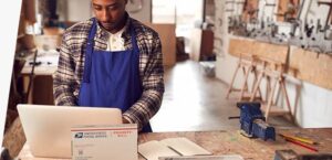 Handwerker organisiert den Versand mit Sendify in Deutschland am Laptop.