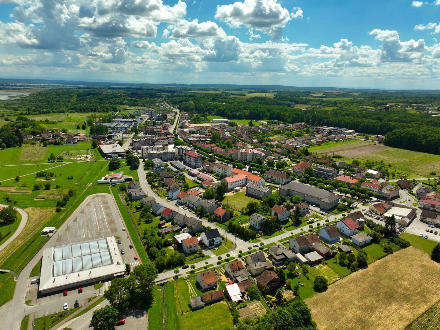 Luftaufnahme eines Dorfes mit Wohnhäusern, Gewerbe und Feldern