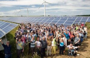 Große Gruppe vor Solarmodulen und Windrädern auf einem Energiepark