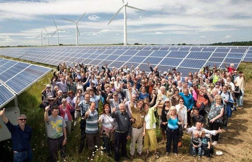 Große Gruppe vor Solarmodulen und Windrädern auf einem Energiepark