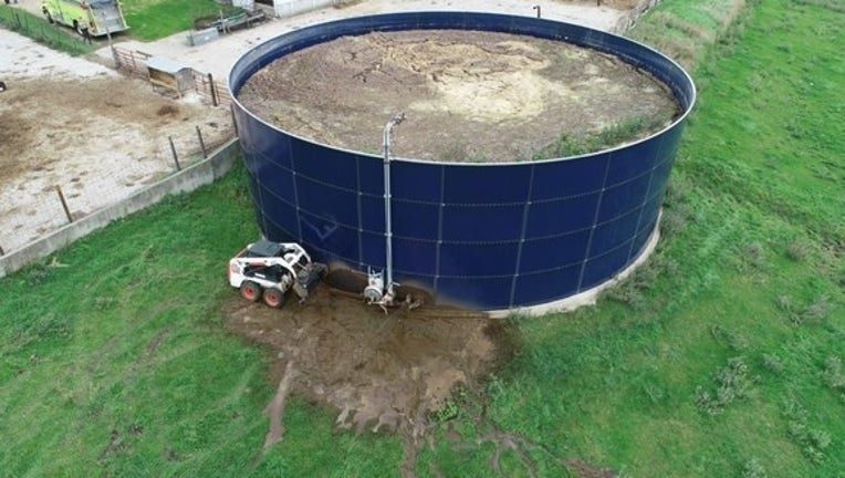 Großer Güllebehälter auf einer landwirtschaftlichen Fläche mit Radlader